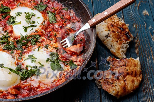 Fried eggs in a frying pan with tomatoes, sausage and greens. Fried eggs in a frying pan with tomatoes, sausage and greens.