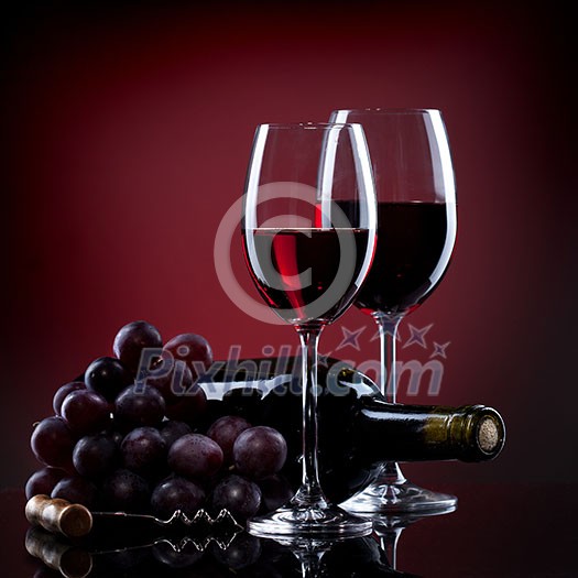 Wine in glasses with grape and bottle on red