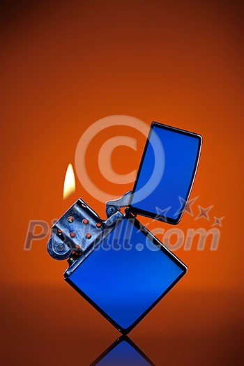 Blue zippo lighter with flame on orange background