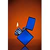 Blue zippo lighter with flame on orange background