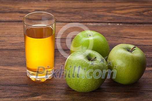 Glass of apple juice and green apples on wooden background Glass of apple juice and green apples on wooden background