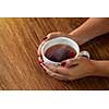 woman holding hot cup of tea on wooden table