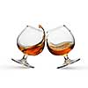 Splash of cognac in two glasses isolated on white background