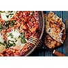 Fried eggs in a frying pan with tomatoes, sausage and greens.