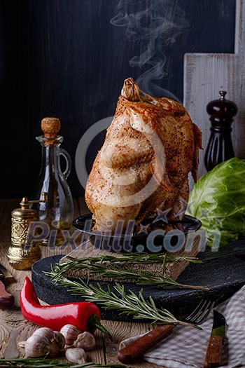 Roasted whole chicken with spices and herbs on a wooden table. Tasty food. Rustic style.