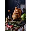 Roasted whole chicken with spices and herbs on a wooden table. Tasty food. Rustic style.