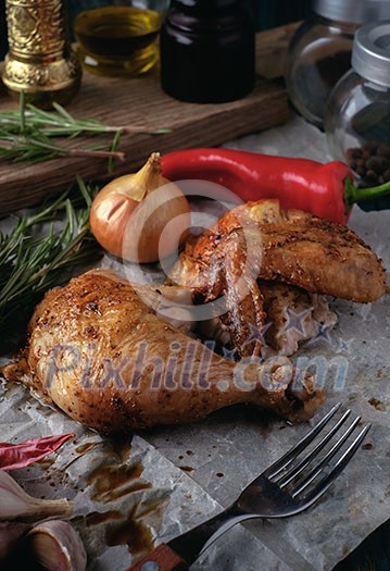 Roasted chicken leg and wing with spices and herbs on a wooden table. Tasty food. Rustic style.