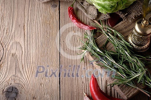 Food background, with herbs, spices, rosemary, papper and vegetables. Wood background.
