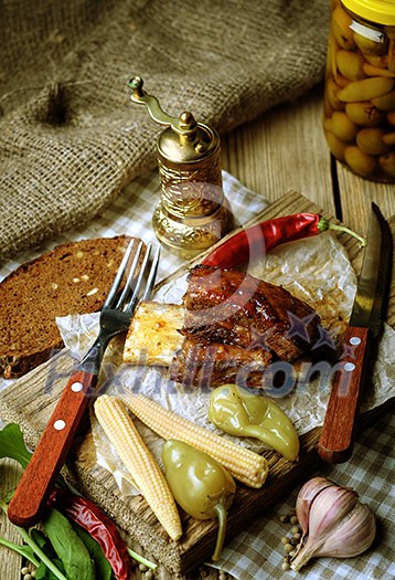 Baked spare ribs with herbs and spices. Wooden background. Rustic style.