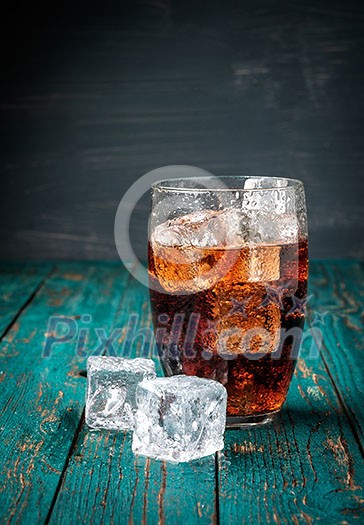 Glass of cola with ice on a wooden table. Copyspace. Glass of cola with ice on a wooden table. Copyspace.