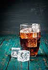 Glass of cola with ice on a wooden table. Copyspace.
