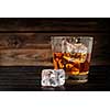 Glass of whiskey with ice on a wooden background. Copyspace on the left.