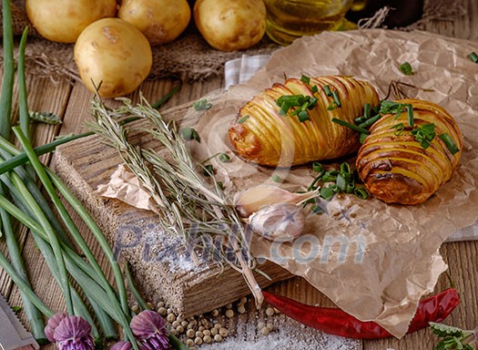 Sliced baked potatoes over wooden background. Rustic style.