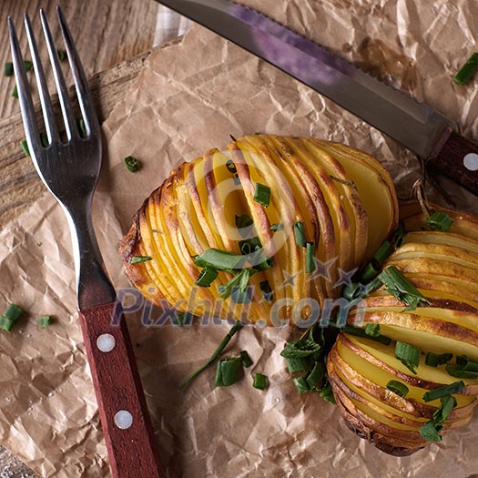 Sliced baked potatoes over wooden background. Rustic style.