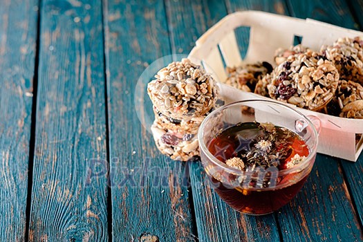 Cup of tea and cookies made of nuts and raisins on the blue wooden table. Kozinaki.