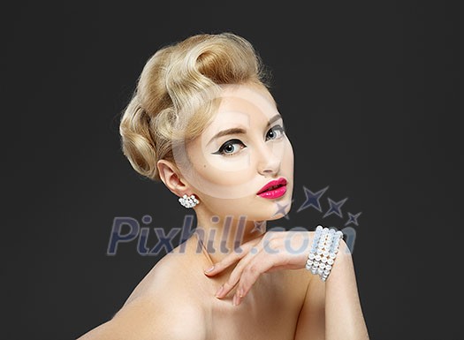 Beautiful young girl with jewels. Makeup in sixties style 'arrow'. Gray background. Hairstyle.