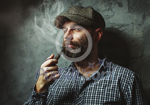 man smokes a pipe standing near the wall.