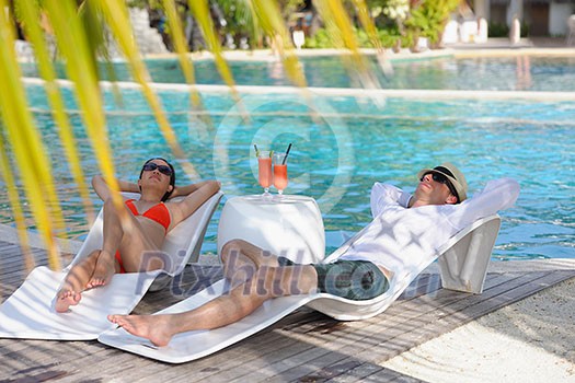 happy young couple relax and take fresh drink at summer vacation on swimmin pool happy young couple relax and take fresh drink at summer vacation on swimmin pool
