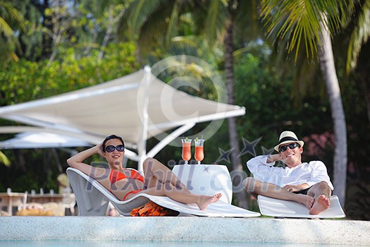 happy young couple relax and take fresh drink at summer vacation on swimmin pool happy young couple relax and take fresh drink at summer vacation on swimmin pool