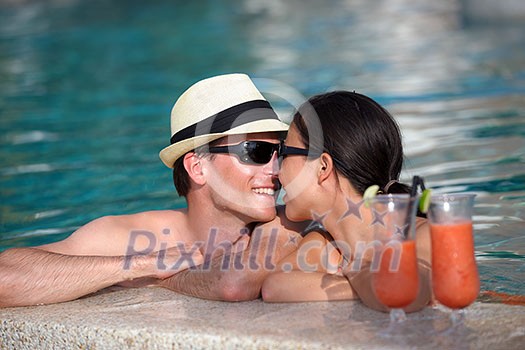 happy young couple relax and take fresh drink at summer vacation on swimmin pool happy young couple relax and take fresh drink at summer vacation on swimmin pool