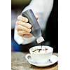 Barista prepares cappuccino in his coffee shop