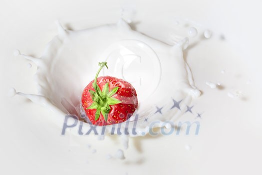 Strawberry dropped into milk with splash