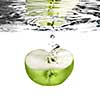 green apple dropped into water with bubbles isolated on white