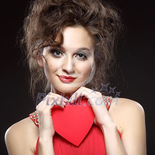 Girl in red dress keeps the heart. Concept of Valentine's Day. Dark background. Girl in red dress keeps the heart. Concept of Valentine's Day. Dark background.