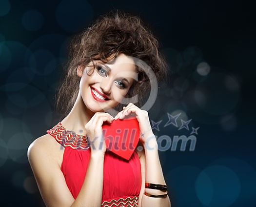 Girl in red dress keeps the heart. Concept of Valentine's Day. Blue background with bokeh