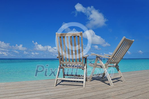 Two chairs beds in forest on tropical beach with blue ocean in background Two chairs beds in forest on tropical beach with blue ocean in background