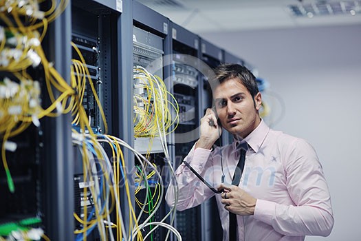 young business man computer science engeneer talking by cellphone at network datacenter server room asking  for help and fast solutions and services