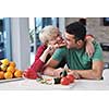 happy young couple have fun in  modern kitchen indoor  while preparing fresh fruits and vegetables food salad