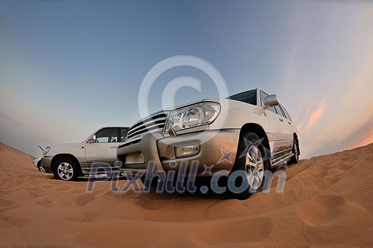 Desert Safari - Off-road jeep vehicles driving in the Arabian Desert at sunset Desert Safari - Off-road jeep vehicles driving in the Arabian Desert at sunset