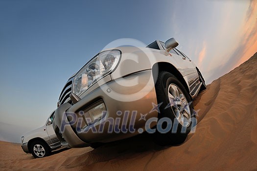 Desert Safari - Off-road jeep vehicles driving in the Arabian Desert at sunset