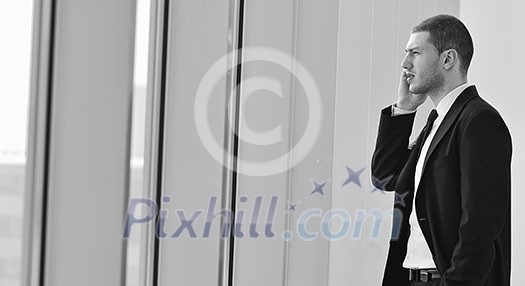 young business man talk by cellphone over bright window in big hall 