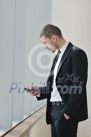 young business man talk by cellphone over bright window in big hall 
