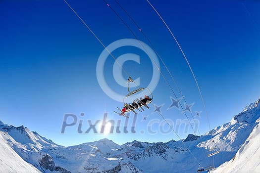 Ski lift - happy skiers use vertical transport  on ski vacation at sunny winter snow day