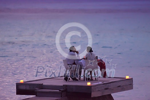 romantic couple  in love have dinner in outdoor restaurant with candles with sea in background