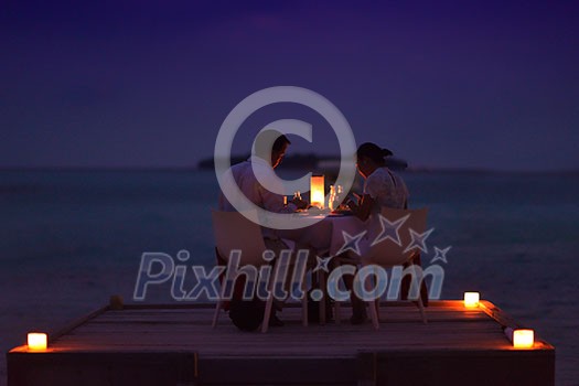 romantic couple in love have dinner in outdoor restaurant with candles with sea in background romantic couple in love have dinner in outdoor restaurant with candles with sea in background
