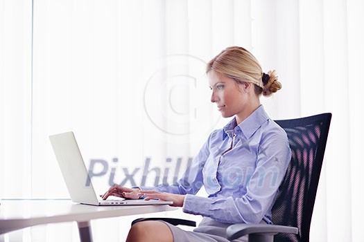 portrait of Young pretty business woman work on notebook computer in the bright modern office indoors portrait of Young pretty business woman work on notebook computer in the bright modern office indoors