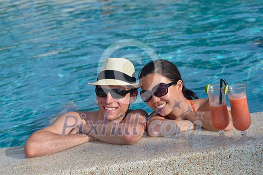 happy young couple relax and take fresh drink at summer vacation on swimmin pool happy young couple relax and take fresh drink at summer vacation on swimmin pool