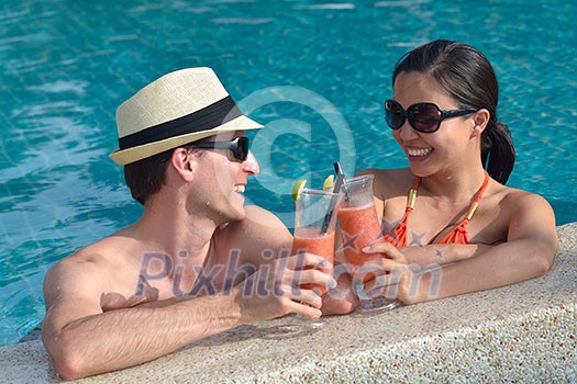 happy young couple relax and take fresh drink at summer vacation on swimmin pool happy young couple relax and take fresh drink at summer vacation on swimmin pool