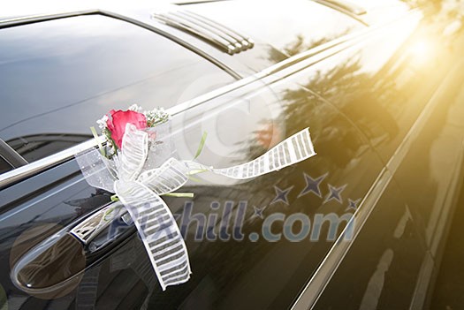 Door of black wedding car with flower and ribbon