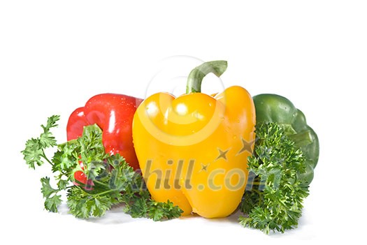 red, yellow and green pepper with parsley isolated on white