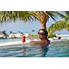 Beautiful young woman in bikini lying on a deckchair with a drink by the sea