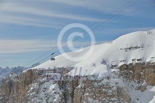 winter landscape with ski chairlift cabin and mountain covered with snow at sunny day