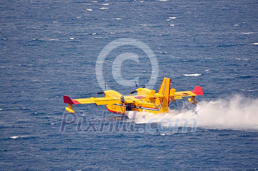 Airplane on sea taking water to drop over fire