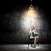 Image of young businesswoman sitting on chair under spot of light