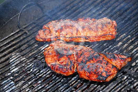 Juicy steaks cooking on a barbeque Juicy steaks cooking on a barbeque
