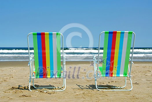 Two colorful beach chairs on the ocean shore